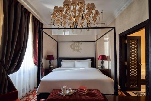 a bedroom with a large white bed and a chandelier at Sofitel Legend Old Cataract in Aswan