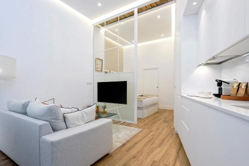 Una sala de estar blanca con un sofá y un televisor. en Genteel Home Castilla IV, en Sevilla