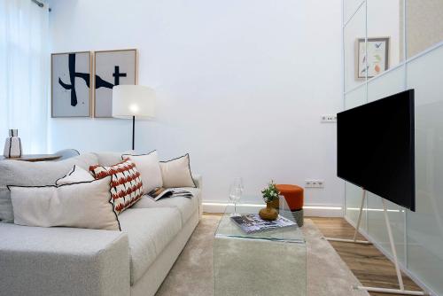 Una sala de estar con un sofá y un televisor de pantalla plana. en Genteel Home Castilla IV, en Sevilla