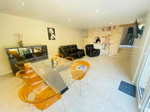 a living room with a glass table and chairs at Maison en pierre de Caen charmante et confortable et sa terrasse privative entre terre et mer in Bretteville-sur-Odon