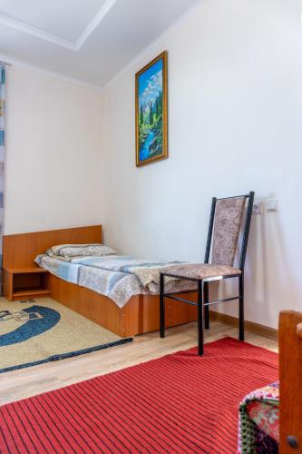 a bedroom with a bed and a chair and a rug at Guest house and yurt camp Svetlana in Bokonbayevo