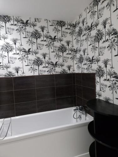 a bathroom with a bath tub with a palm tree wallpaper at La maison des vendangeurs in Libourne