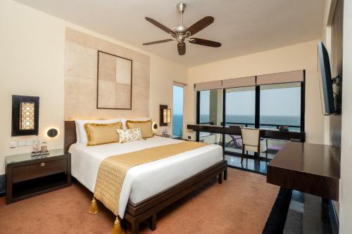 a bedroom with a bed and a desk and a table at The Leela Kovalam, A Raviz Hotel in Kovalam