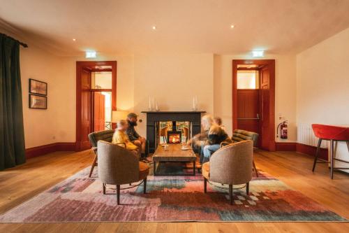a group of people sitting in a living room with a fireplace at Plas Weunydd in Blaenau-Ffestiniog