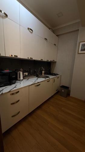cocina grande con armarios blancos y suelo de madera en Rustaveli Luxe Residence, en Tiflis