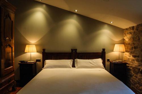 a bedroom with a large bed with two lamps at Hotel Rural Nobles de Navarra in Áibar