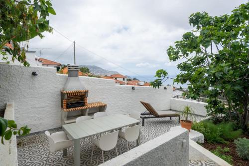 a patio with a table and chairs on a white wall at Casa Imaculado Coração by An Island Apart in Funchal