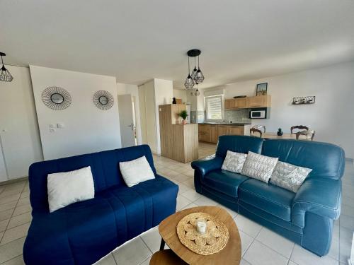 un salon avec deux canapés bleus et une table dans l'établissement Appartement spacieux avec balcon - à 50m de la plage, à Courseulles-sur-Mer