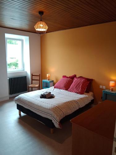 a bedroom with a bed with red pillows and a window at Rosalie's House in Pommerit-Jaudy