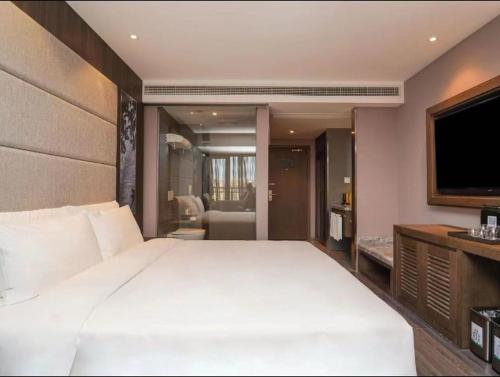 a bedroom with a large white bed and a television at Crystal Orange Shanghai Lingang Ocean Park Hotel in Nianbalian
