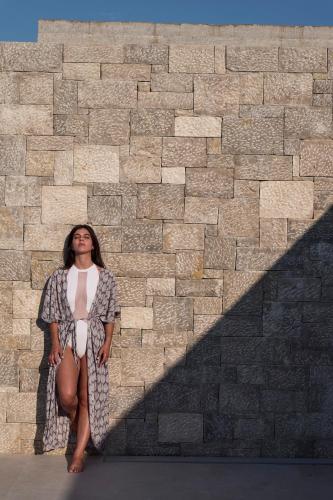 a woman is standing in front of a brick wall at Noero Villas Lefkada in Lefkada Town