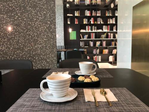 a table with two cups of coffee and a tray of cookies at Insio Hotel in Shenzhen