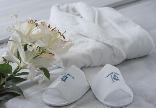a pair of white slippers next to a towel and flowers at Dore Boutique Hotel in Agia Marina Nea Kydonias