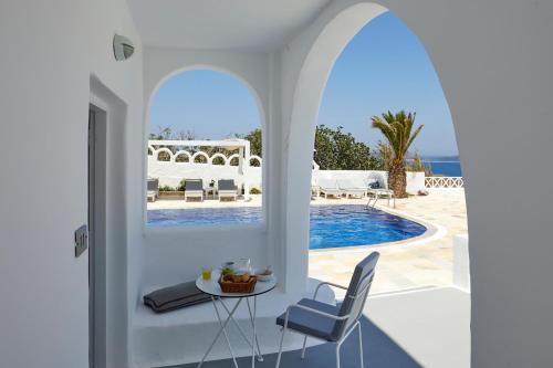 una stanza bianca con un tavolo, sedie e una piscina di Santorini View ad Akrotírion