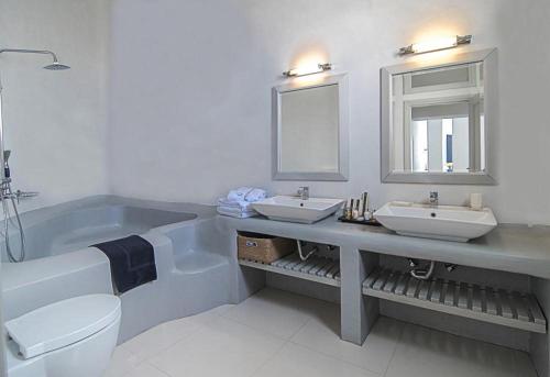 a bathroom with two sinks and a tub and a toilet at Grand Ambassador Santorini Hotel in Akrotiri
