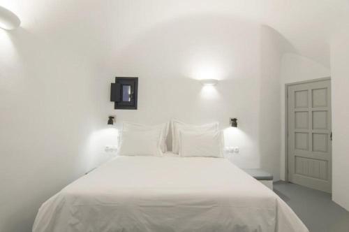 a white bedroom with a bed with white sheets and pillows at Grand Ambassador Santorini Hotel in Akrotiri