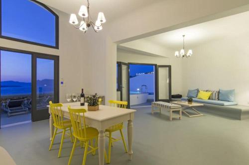 a living room with a dining table and yellow chairs at Grand Ambassador Santorini Hotel in Akrotiri