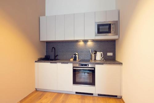 a kitchen with white cabinets and a microwave at LeonArt Living 34 in Graz