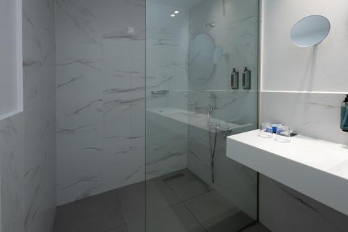 a white bathroom with a glass shower and a sink at Dore Boutique Hotel in Agia Marina Nea Kydonias