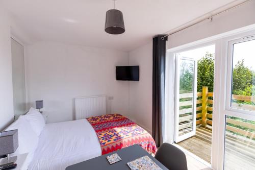 a bedroom with a bed and a window and a desk at Glastonbury- Tor View- Studio in Glastonbury