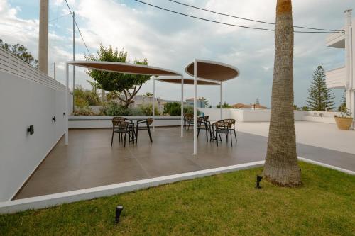 a patio with tables and chairs and a palm tree at Dore Boutique Hotel in Agia Marina Nea Kydonias