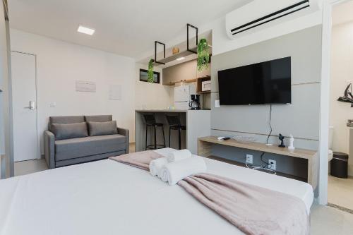 a white bedroom with a large bed and a television at Allure Residence by Carpediem in Recife