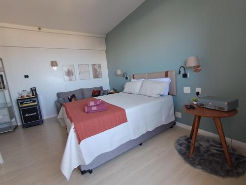 a bedroom with a large white bed with a table at Helbor Stay Santos Pompéia Gonzaga - Varanda vista mar in Santos