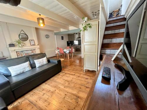 a living room with a black couch and wooden floors at Duplex au lin in Saint-Pol-de-Léon