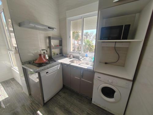 Stylish Coastal Stay with Panoramic Sea Views في طنجة: مطبخ صغير مع مغسلة وغسالة ملابس