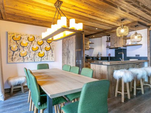 une salle à manger avec une table en bois et des chaises vertes dans l'établissement Luxueux appartement avec piscine, WiFi et parking à Val-d'Isère - FR-1-694-102, à Val dʼIsère
