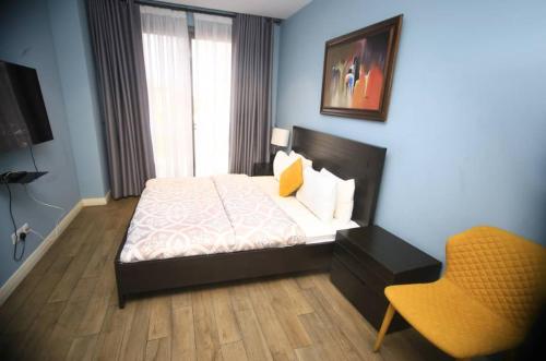 a bedroom with a bed and a chair in it at Pearl of Love Apartment in Accra