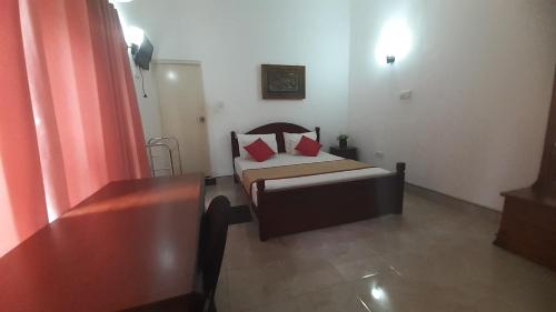 a small bedroom with a bed with red pillows at The Garden Resort Airport Katunayaka in Katunayake
