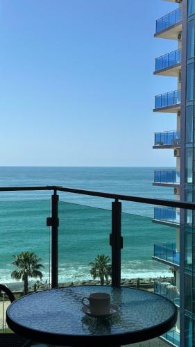 a table with a coffee cup on a balcony with the ocean at Aqua Batumi 84 in Batumi