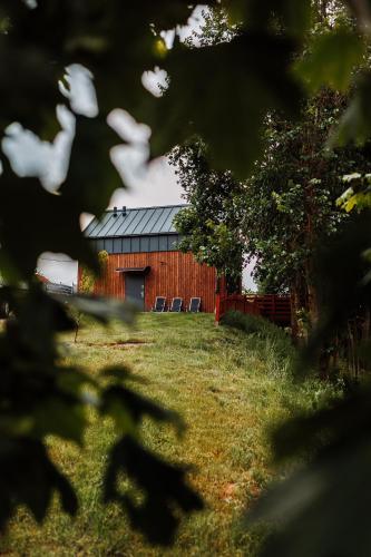 a red barn with two chairs in front of it at Stodoła nad wodą in Olecko Małe