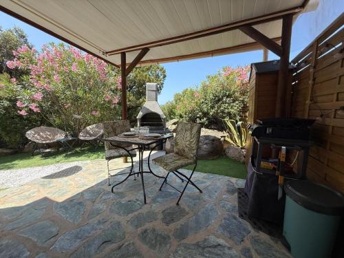 un patio avec une table, des chaises et un barbecue dans l'établissement Studio de charme à 300 m de la Plage de Santa Giulia, à Porto-Vecchio