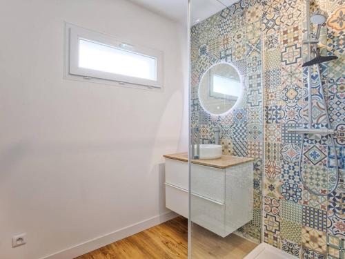 une salle de bain avec une douche avec un lavabo et un miroir dans l'établissement Maisonnette cosy indépendante au centre de Merville-Franceville - FR-1-788-64, à Merville-Franceville-Plage