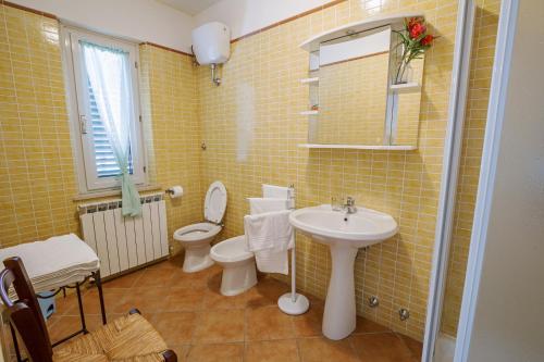 a bathroom with a sink and a toilet and yellow tiles at B&B Centro Ippico Andrea in Porto Recanati
