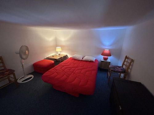 une chambre avec un lit rouge et deux chaises et une lampe dans l'établissement Charmant T2 à 1200m de la plage avec balcon, parking privé et ménage inclus à Saint-Jean-de-Monts - FR-1-224C-312, à Saint-Jean-de-Monts