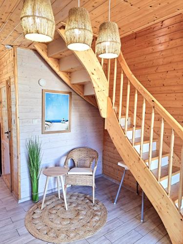 a wooden staircase in a cabin with a table and a chair at Tropikana Domki, Apartamenty in Mielno