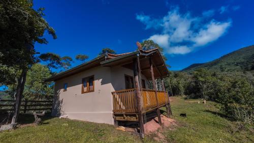 a small house with a balcony on a hill at Chalé Morada das estrelas in Aiuruoca