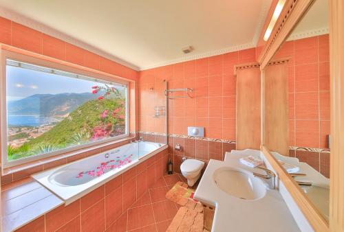 Un baño con bañera, inodoro y ventana. en Villa Noyan, en Kas
