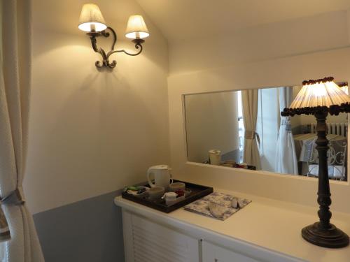 a bathroom with a mirror and a lamp on a counter at La Villa des Charmilles in Vernoux-en-Vivarais