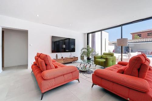 - un salon avec deux chaises rouges et une télévision à écran plat dans l'établissement Modern villa with pool, à Narbonne