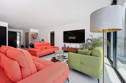 un salon avec des meubles orange et verts et une lampe dans l'établissement Modern villa with pool, à Narbonne