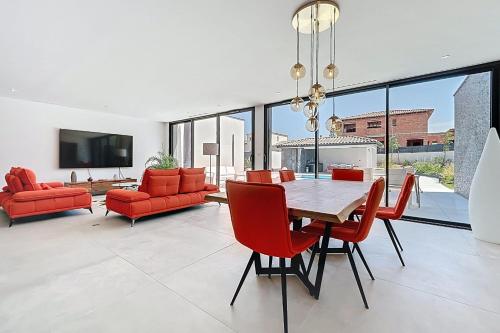 une salle à manger avec des chaises rouges et une table dans l'établissement Modern villa with pool, à Narbonne