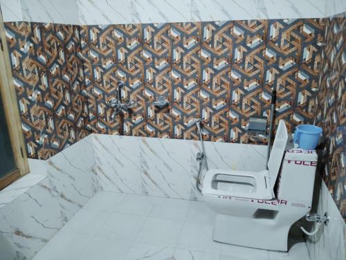 a bathroom with a toilet and a mosaic wall at Idress home stay hunder in Hundar
