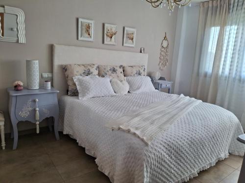 a bedroom with a white bed and a chandelier at Habitación en casa moderna con jardín in Santa Cruz de Bezana