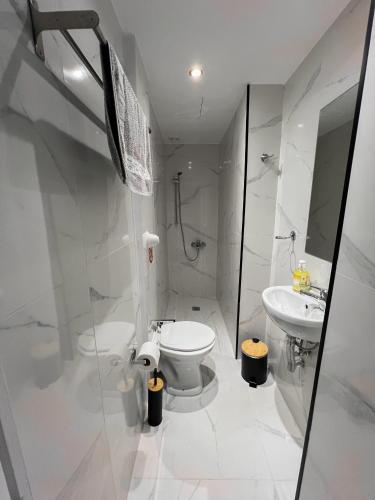 a white bathroom with a toilet and a sink at Nami Sea View Near Airport Apartment in Artemida
