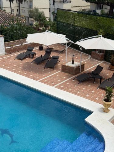 a swimming pool with umbrellas and chairs and a pool at Amaca in Mijas Costa
