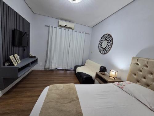 a bedroom with a bed and a couch and a television at Loft Arara Manaus in Manaus